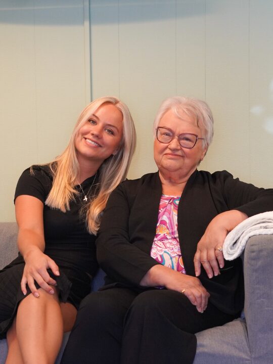Josefine och Pirkko-Lisa Vihtari sitter i en soffa och ler